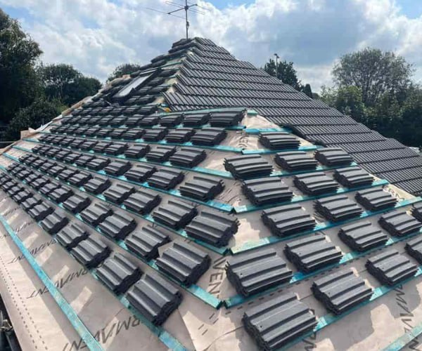 This is a photo of a new hip roof being installed. New felt, battens, and grey tiles have been installed, also a new velux window. Works carried out by BN Roofing Letchworth Garden City